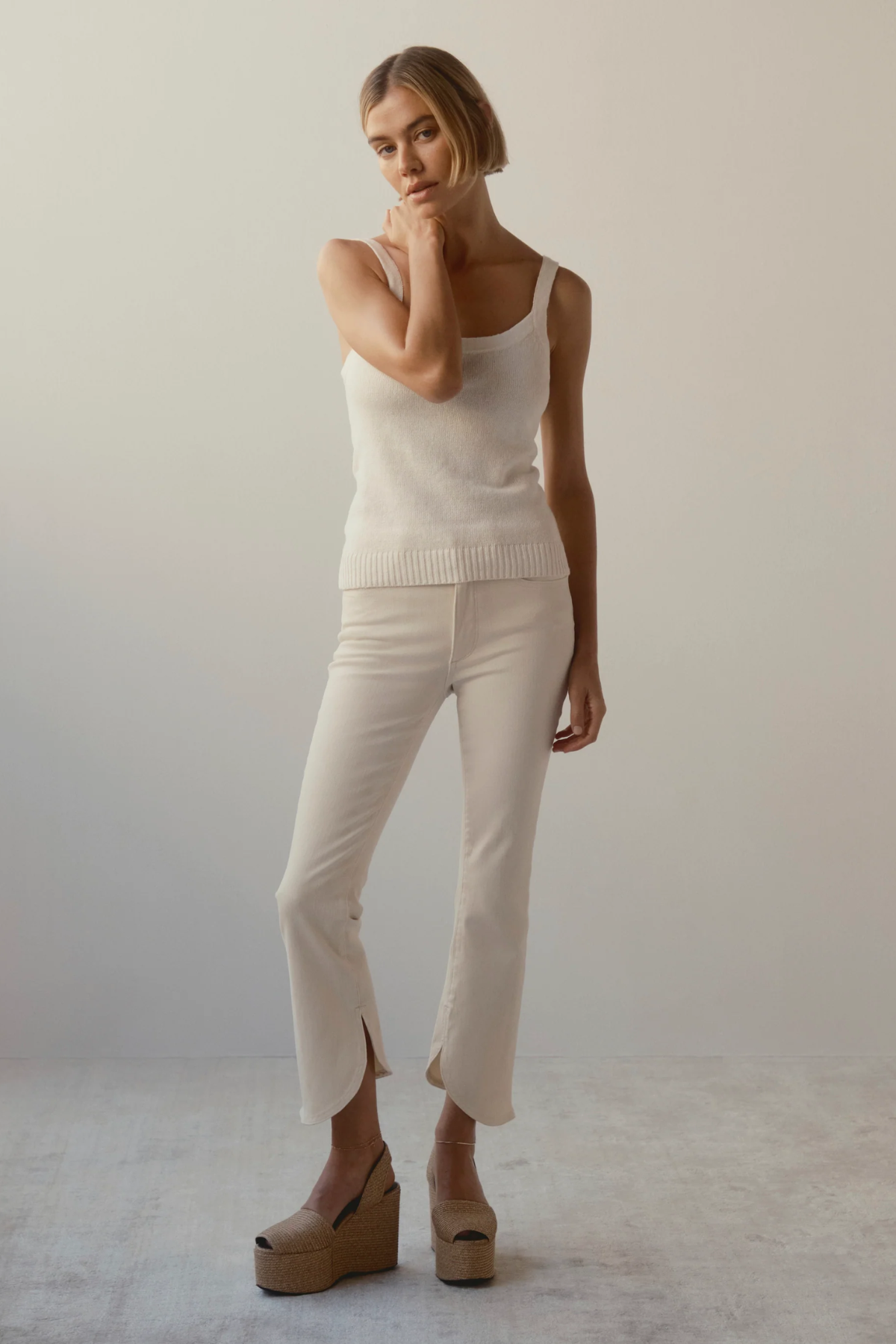 woman in cream outfit and wedges on tan background 