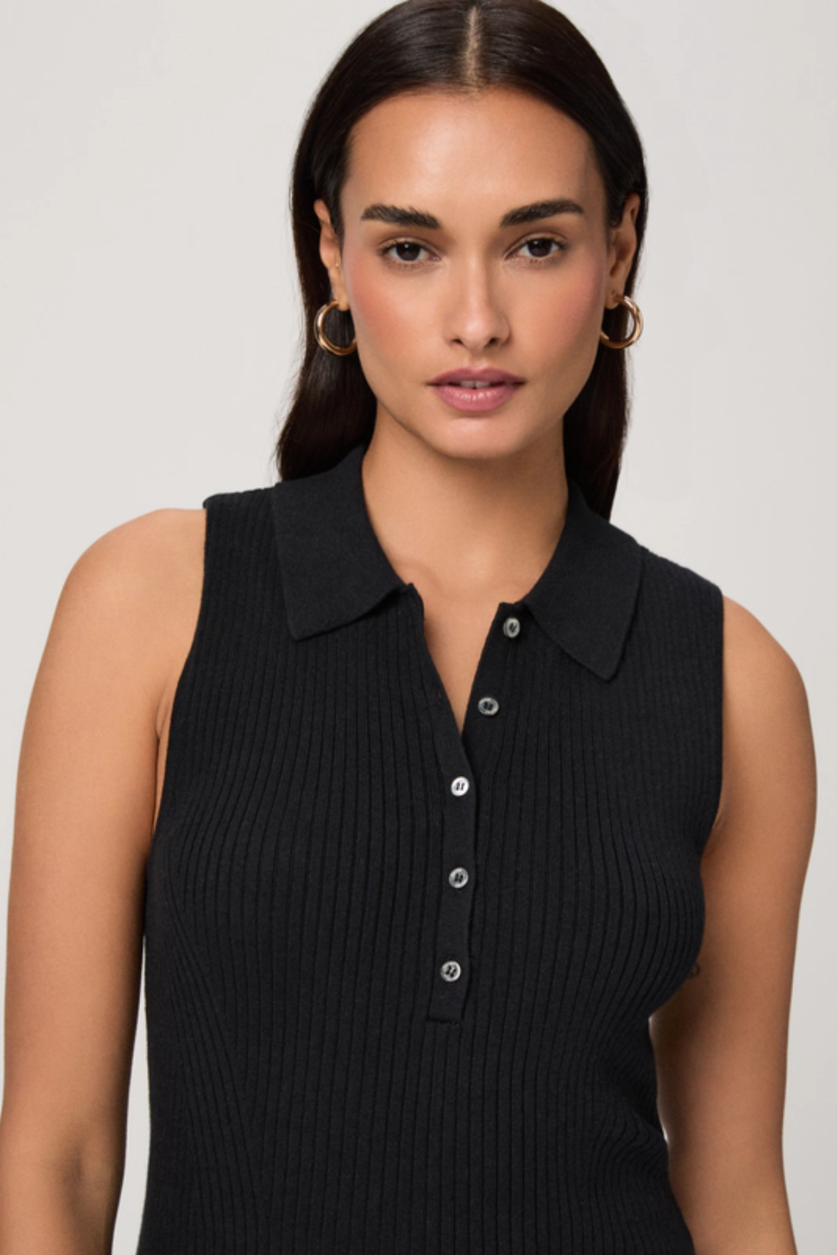 Woman wearing a black sleeveless ribbed top against a plain background