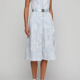 Woman wearing a light blue patterned dress on a plain background