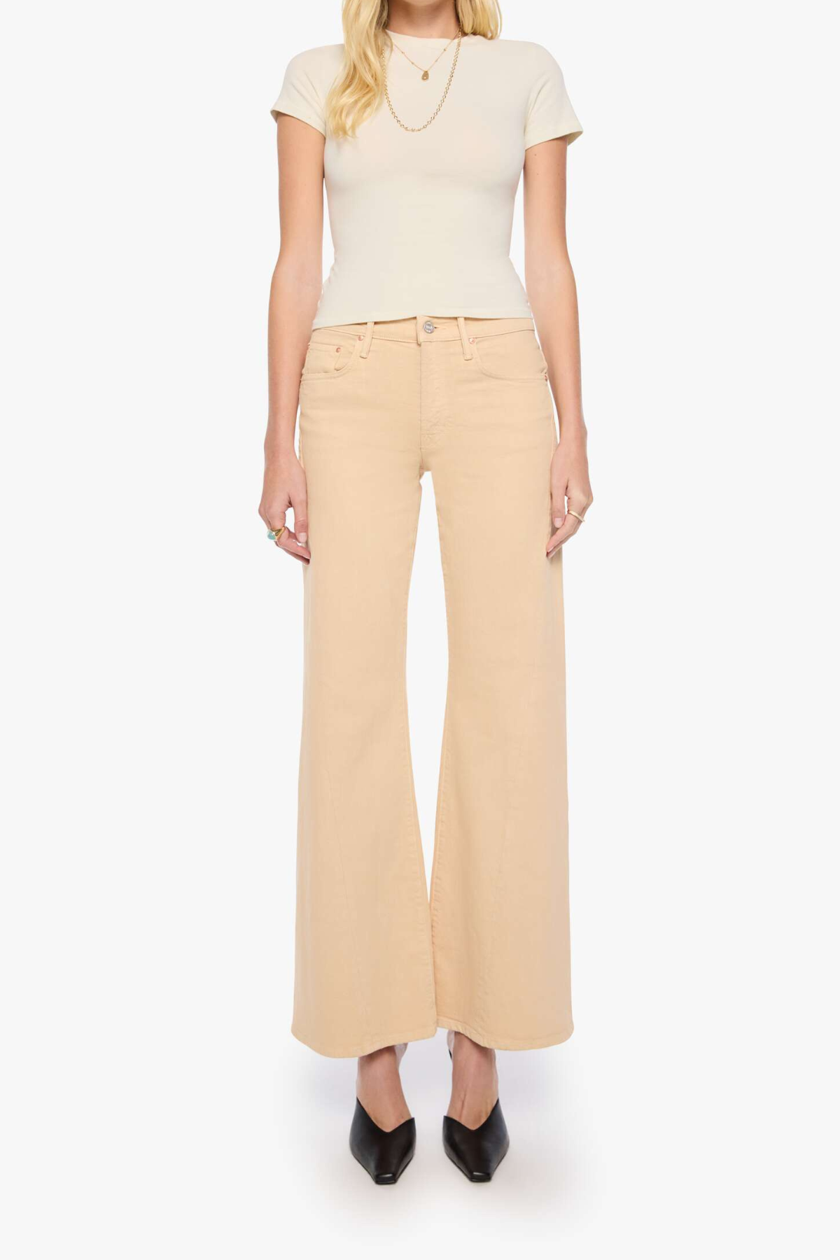 A model wearing a cream short-sleeve top and light beige wide-leg cropped pants with black pointed-toe heels, shown against a plain white studio background.