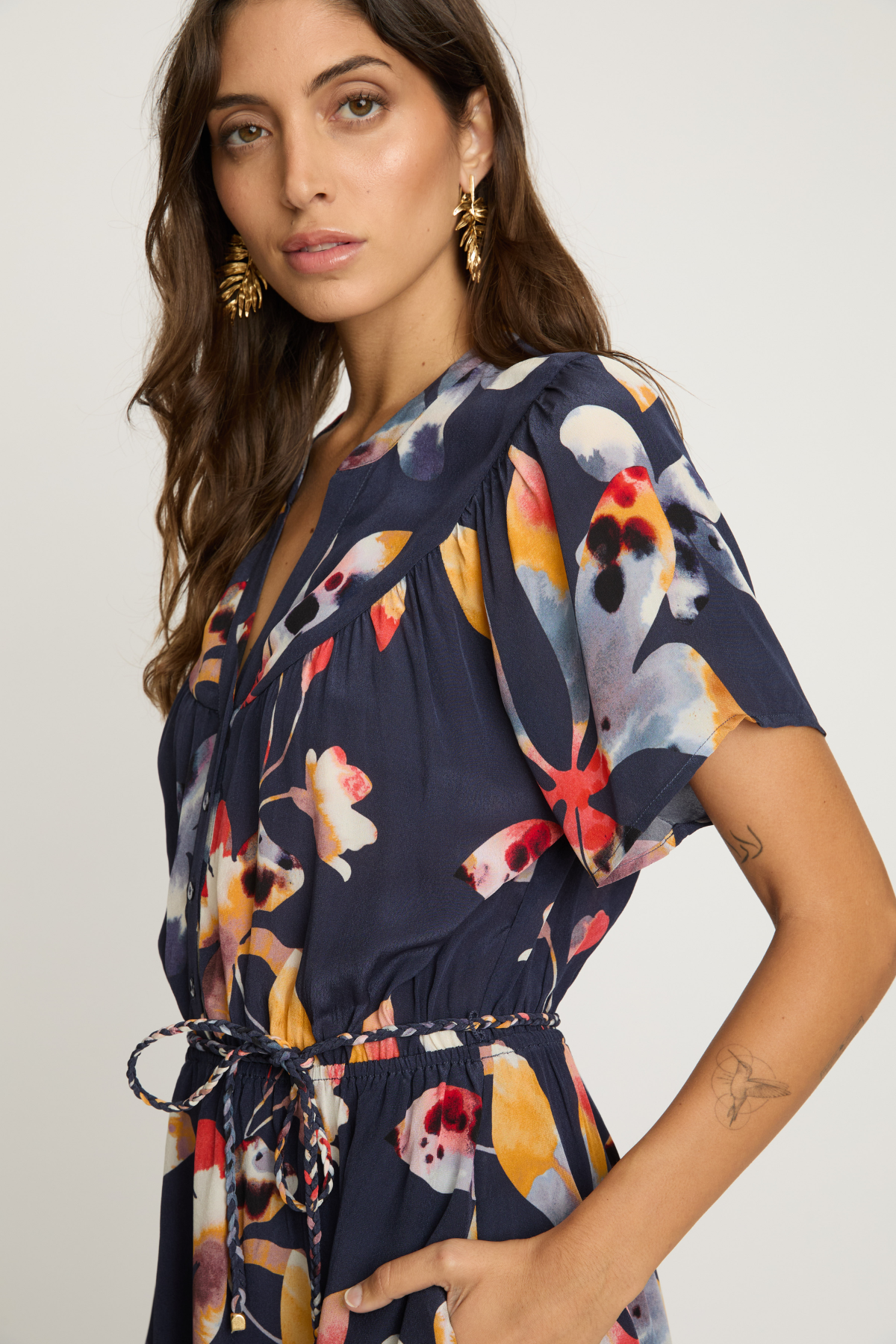 Woman wearing a navy dress with colorful floral pattern on a plain background