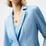 Woman wearing a light blue textured blazer against a white background