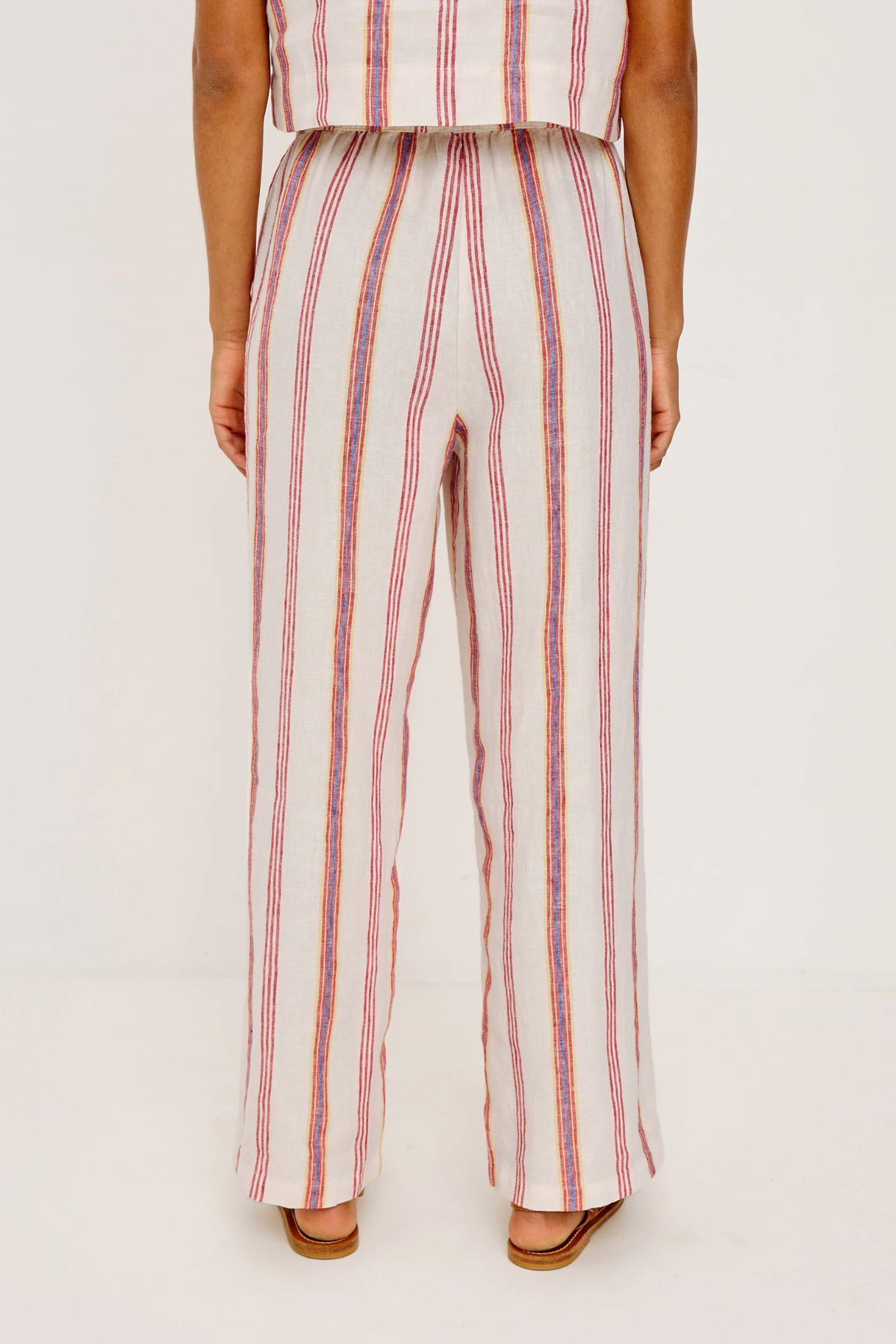 Person wearing a striped outfit with wide-leg pants on a white background