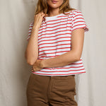 Woman wearing a red and white striped shirt with brown pants against a neutral background