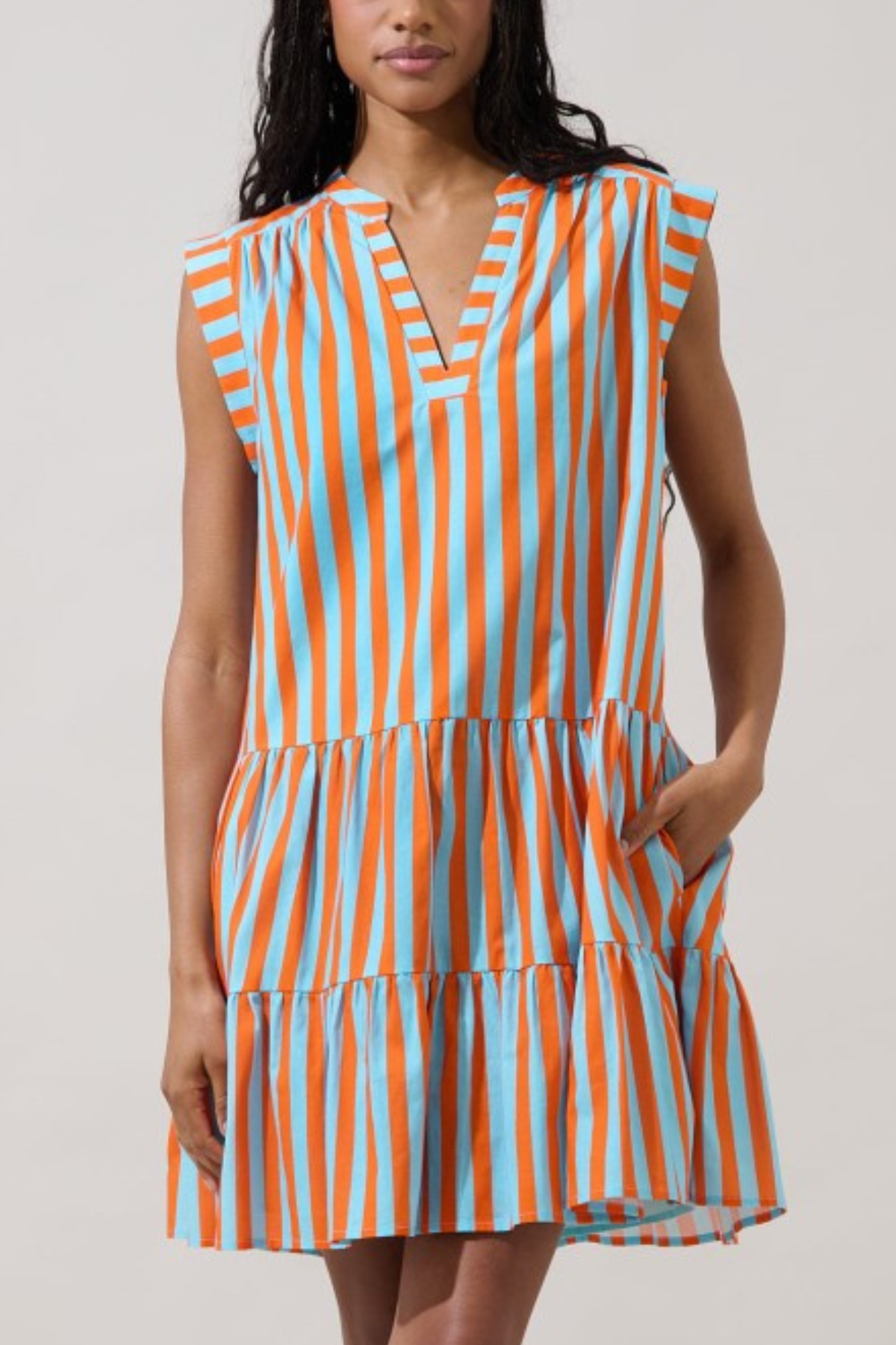 model wearing Sleeveless tiered midi dress featuring vertical orange, blue, and cream stripes with a relaxed, flowing silhouette.