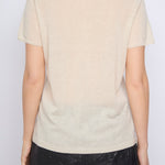 Person wearing a beige t-shirt with a subtle pattern on a plain background