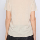 Person wearing a beige t-shirt with a subtle pattern on a plain background