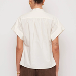 Person wearing a white shirt and brown pants against a white background
