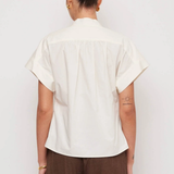 Person wearing a white shirt and brown pants against a white background