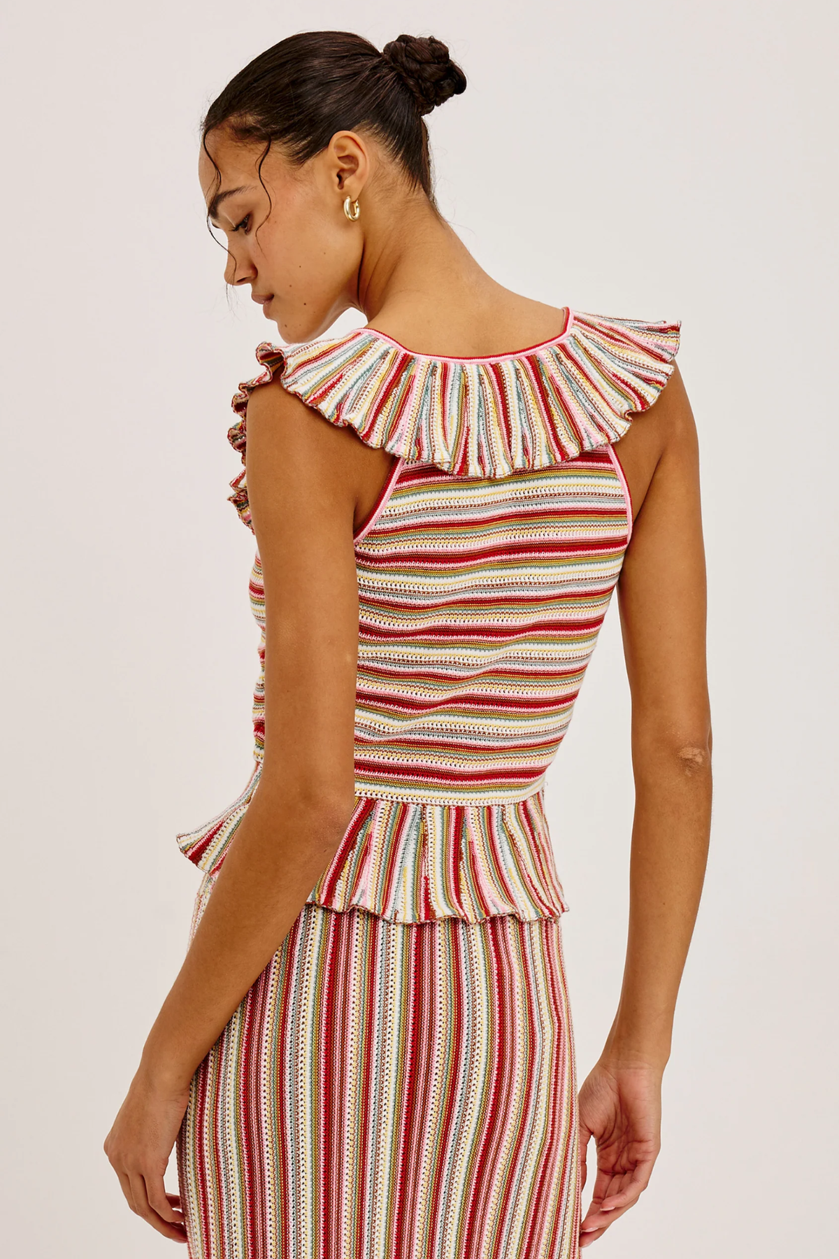 Woman wearing a striped sleeveless top with ruffled details on a white background