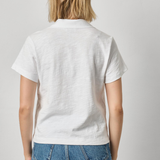 Person wearing a white polo shirt and blue jeans on a plain background