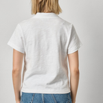 Person wearing a white polo shirt and blue jeans on a plain background