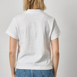 Person wearing a white polo shirt and blue jeans on a plain background