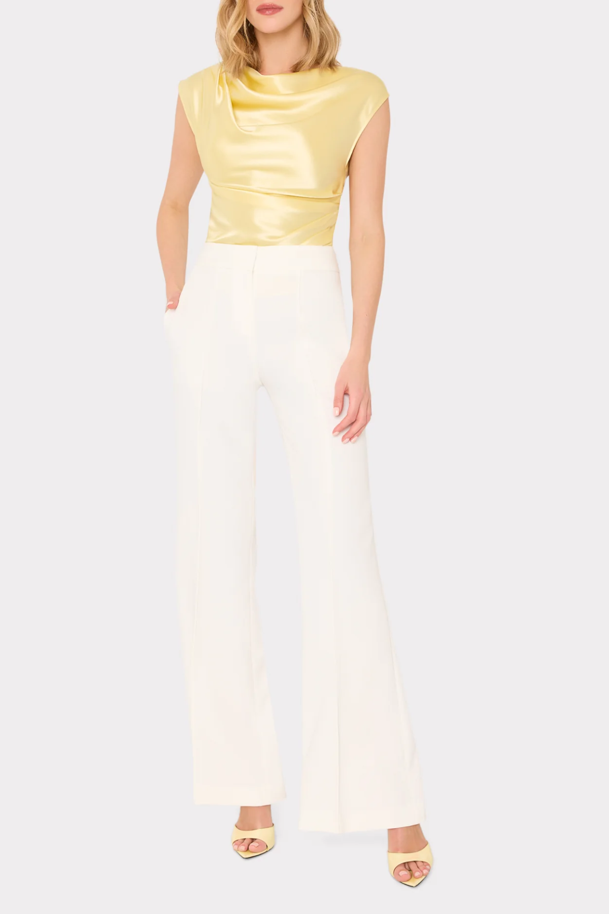 Woman wearing a yellow top and white pants on a white background