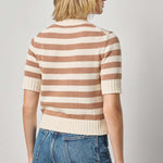 Person wearing a striped sweater and jeans on a plain background
