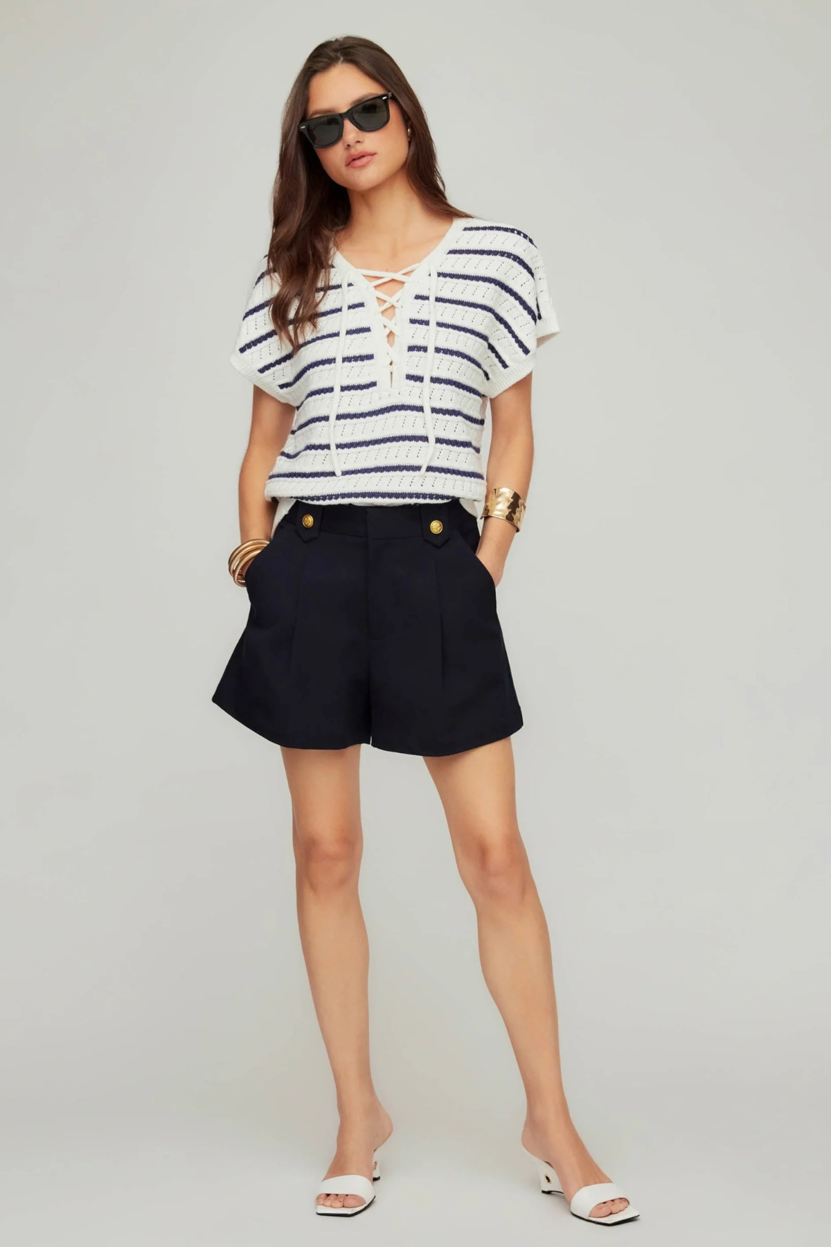 Woman wearing a striped shirt and black shorts on a plain background