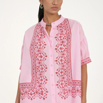 Woman wearing a pink embroidered outfit on a white background