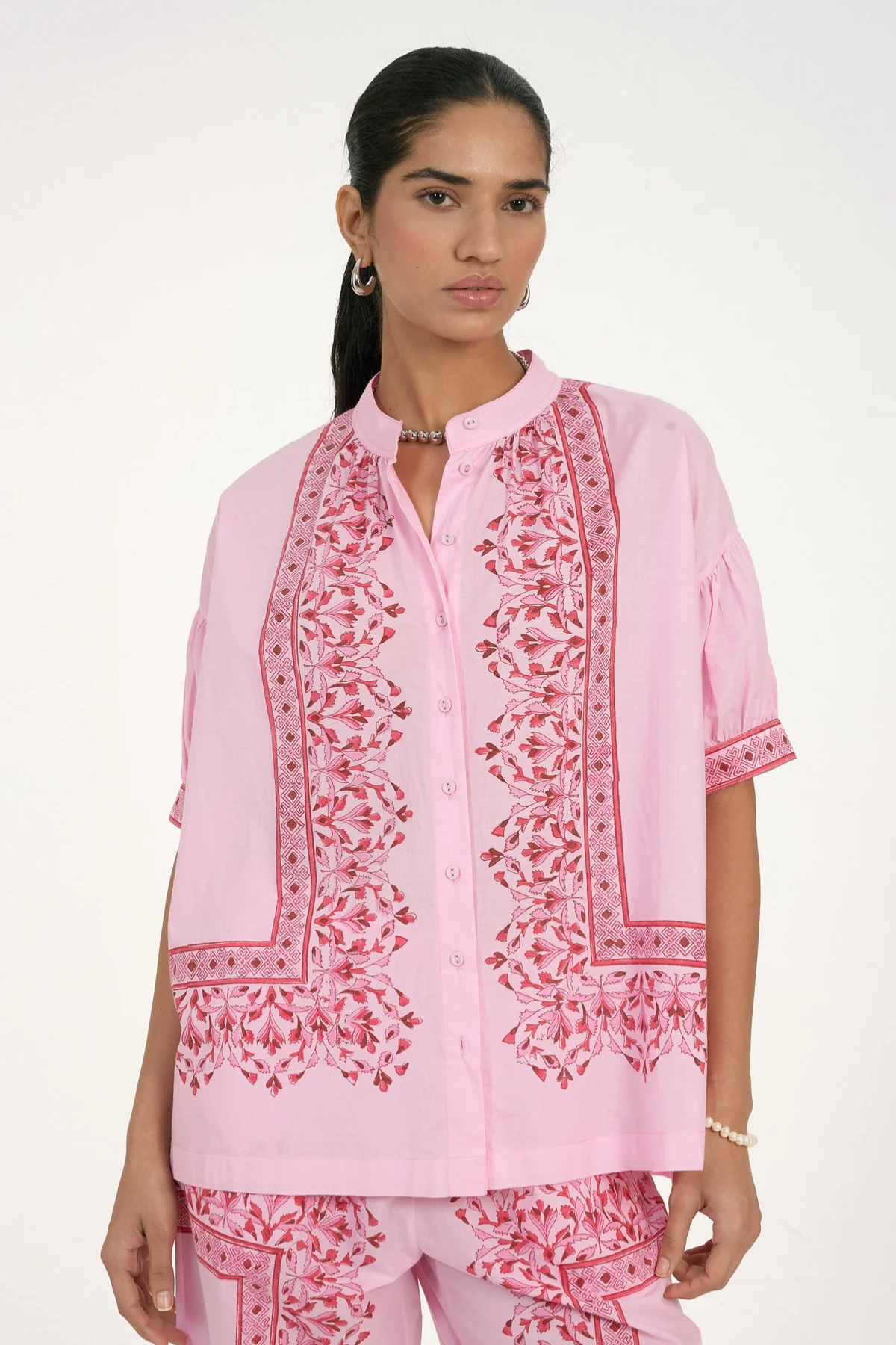 Woman wearing a pink embroidered outfit on a white background