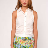 Woman wearing a white sleeveless shirt and colorful floral skirt on a white background