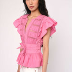 Woman wearing a pink blouse with ruffled sleeves on a white background