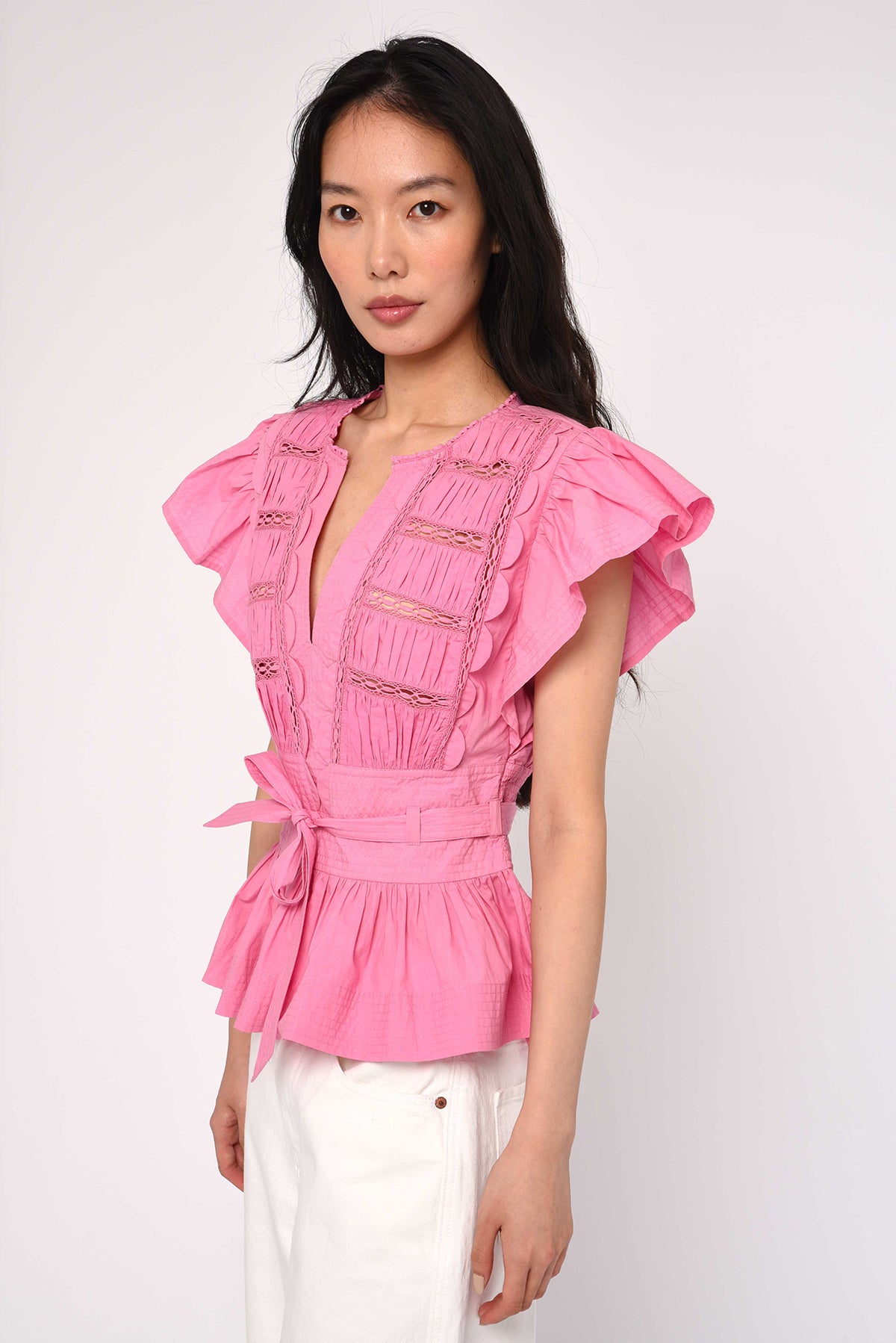Woman wearing a pink blouse with ruffled sleeves on a white background