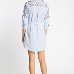 Woman wearing a light blue dress with lace details on a white background