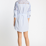 Woman wearing a light blue dress with lace details on a white background