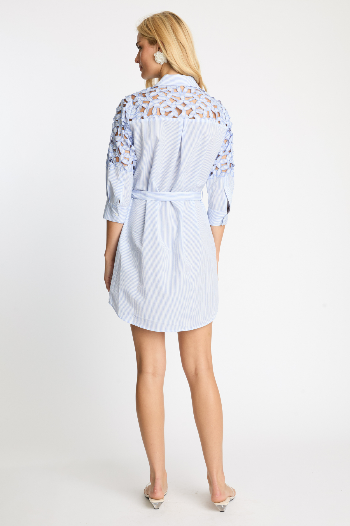 Woman wearing a light blue dress with lace details on a white background