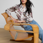 Woman sitting on a modern wooden chair with a neutral background