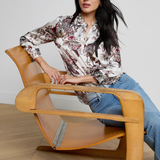 Woman sitting on a modern wooden chair with a neutral background