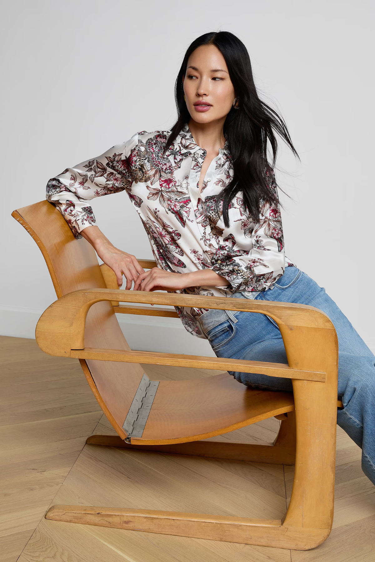 Woman sitting on a modern wooden chair with a neutral background