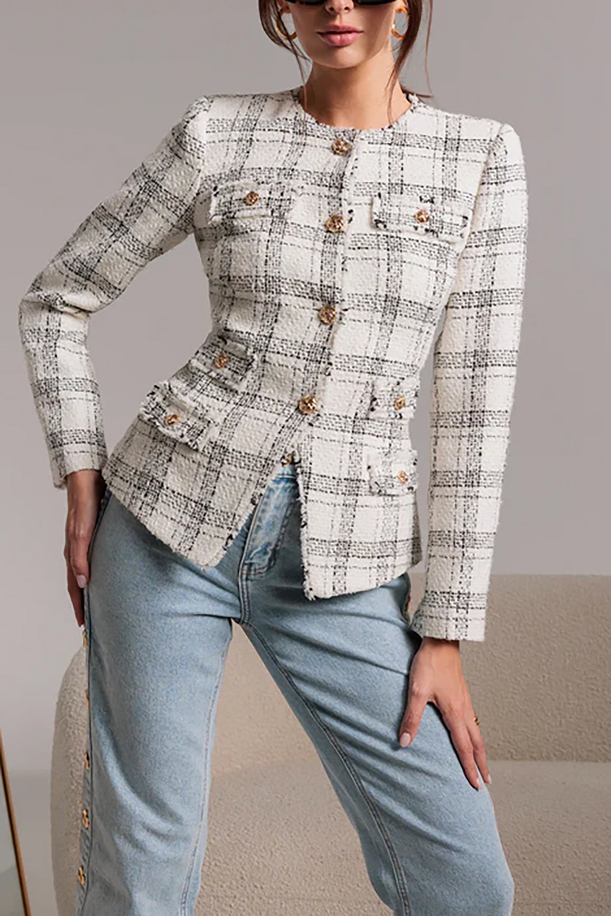 Person wearing a patterned blazer and light blue jeans against a neutral background