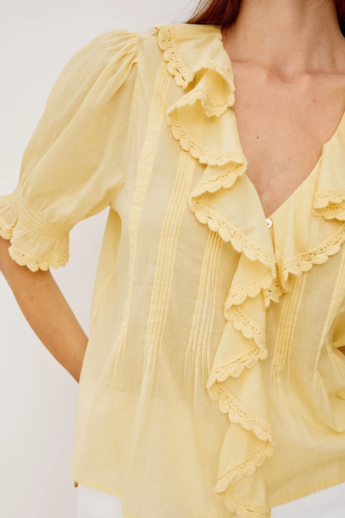 Yellow blouse with ruffled details on a white background