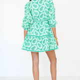 back of woman in green mini dress on white background 
