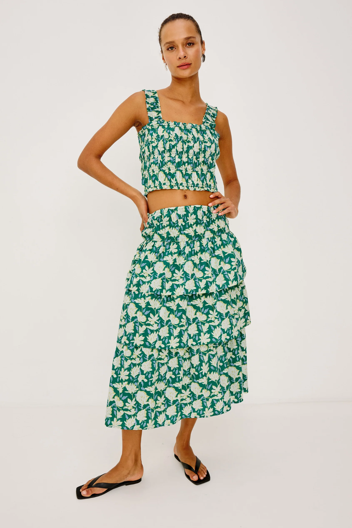 Woman wearing a green floral two-piece outfit on a white background