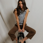 Woman sitting on a black stool against a plain white background