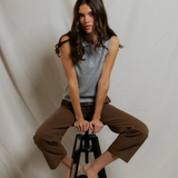 Woman sitting on a black stool against a plain white background