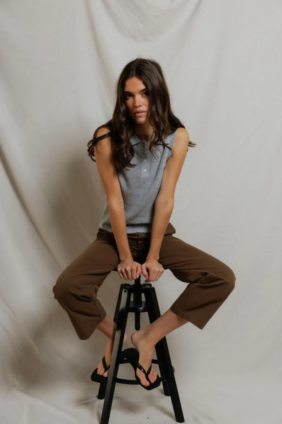 Woman sitting on a black stool against a plain white background