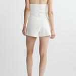 Person wearing a white halter top and shorts on a plain background