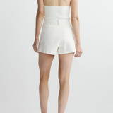 Person wearing a white halter top and shorts on a plain background