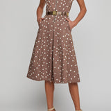 Woman wearing a brown dress with white polka dots on a gray background