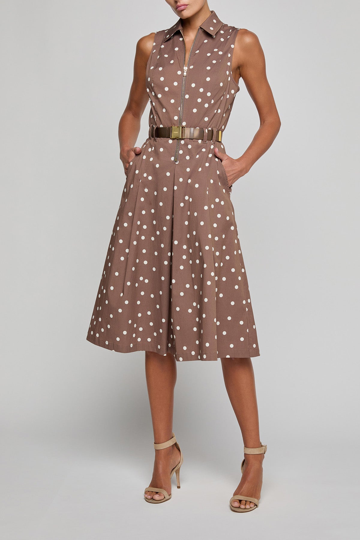 Woman wearing a brown dress with white polka dots on a gray background