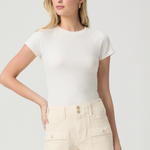 Woman wearing a white top and beige shorts on a plain background