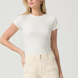 Woman wearing a white top and beige shorts on a plain background