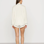 Person wearing a white long-sleeve shirt and shorts on a plain background