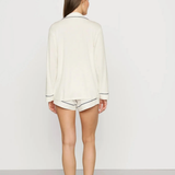 Person wearing a white long-sleeve shirt and shorts on a plain background