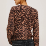 A woman shown from the back wearing a fuzzy leopard-print sweater and dark jeans against a plain light background.