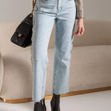 Person wearing light blue jeans and black ankle boots, holding a black handbag.