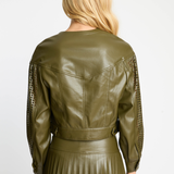 Person wearing an olive green leather jacket with lace sleeves on a white background