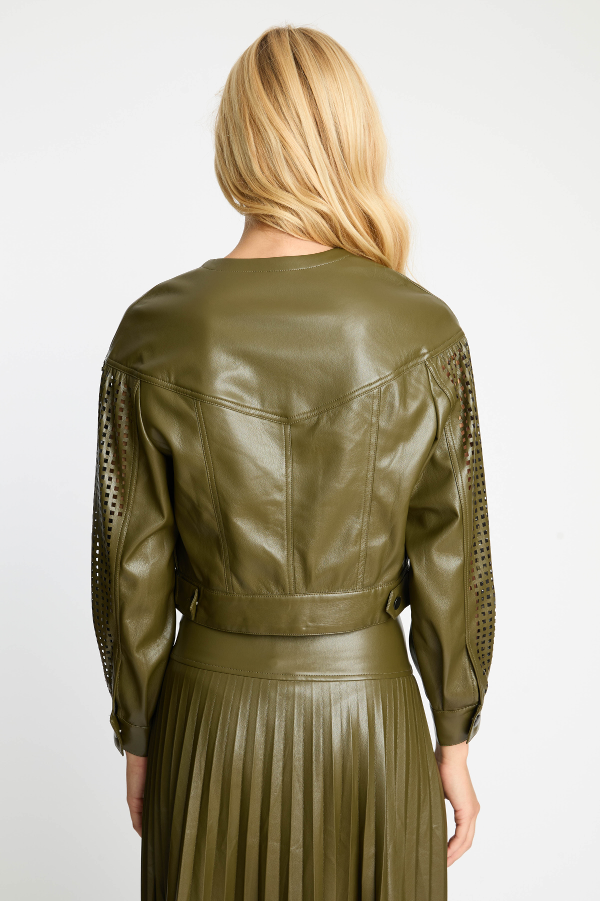 Person wearing an olive green leather jacket with lace sleeves on a white background